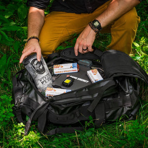 Unpacking the survival bag gear in the grass
