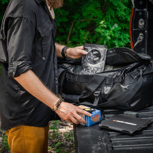 Loading the survival bag with gear on a truck tailgate