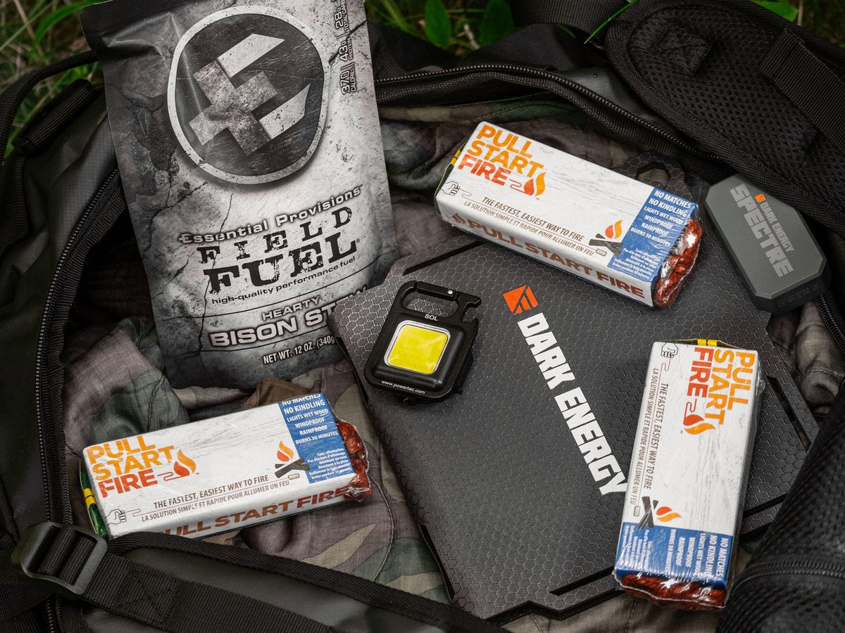 The free survival bag opened up: bison stew MRE, Pull Start fire starters, Dark Energy Spectre solar panel and Powertac SOL keychain light inside the Defcon 5 duffle